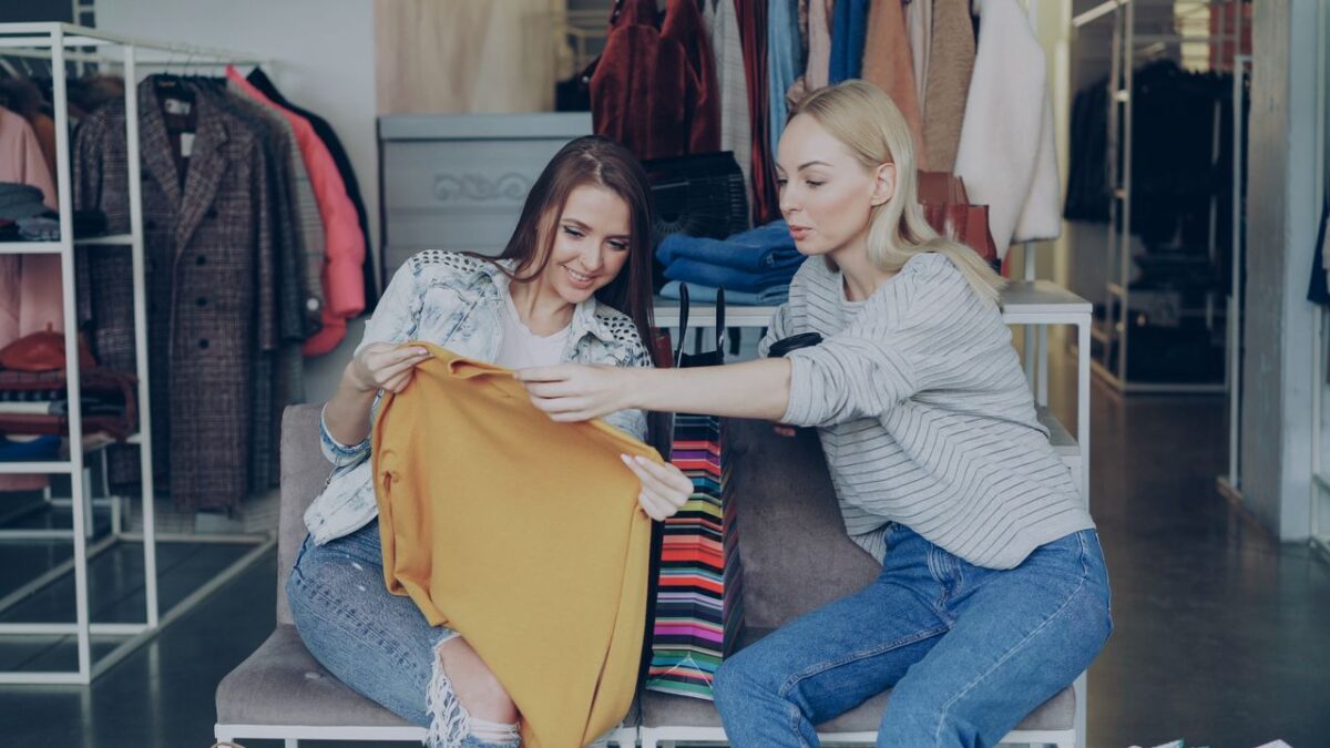 Two women shopping and examining clothes in a fashion boutique, enjoying their retail experience.