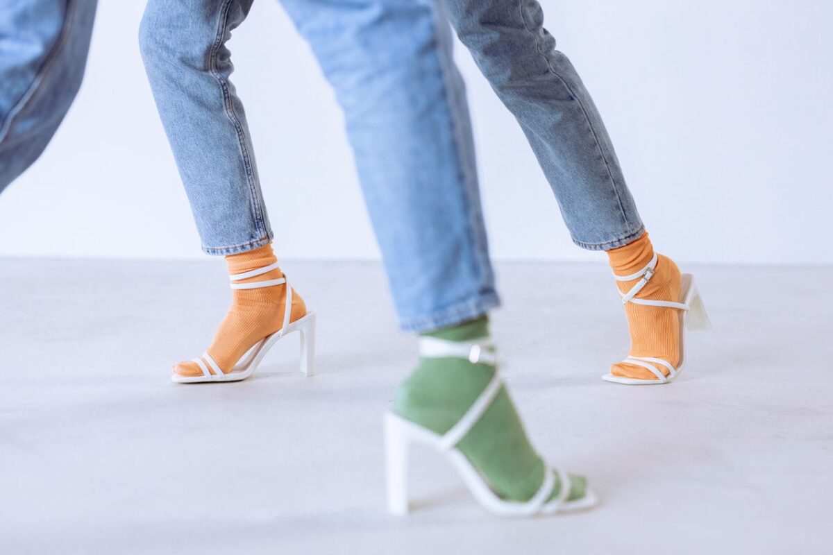 Stylish heeled sandals with colorful socks paired with denim jeans in a studio setting.